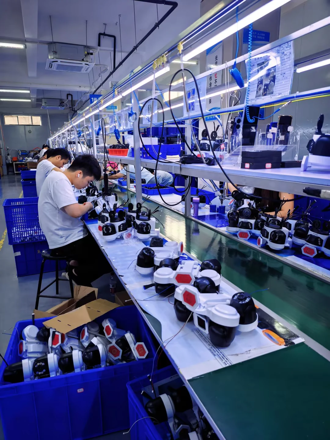 Technicians assembling security cameras at production workstations
